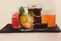 Un grupo de vasos llenos de diferentes tipos de bebidas en una bandeja.