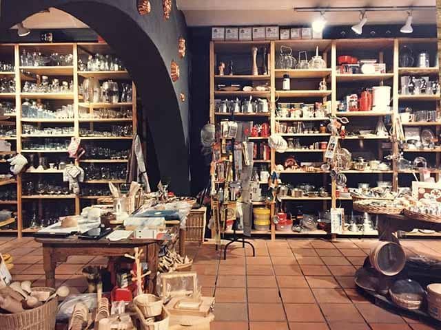 Una tienda llena de muchos artículos, incluida una mesa y estantes.