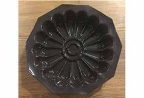 Un molde para pastel negro con un diseño de flores se encuentra sobre una mesa de madera.