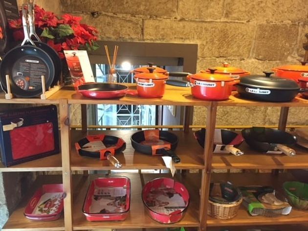 Un estante lleno de ollas y sartenes, incluida una que dice 
