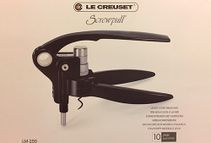 Hay un sacacorchos negro en una caja sobre una mesa.