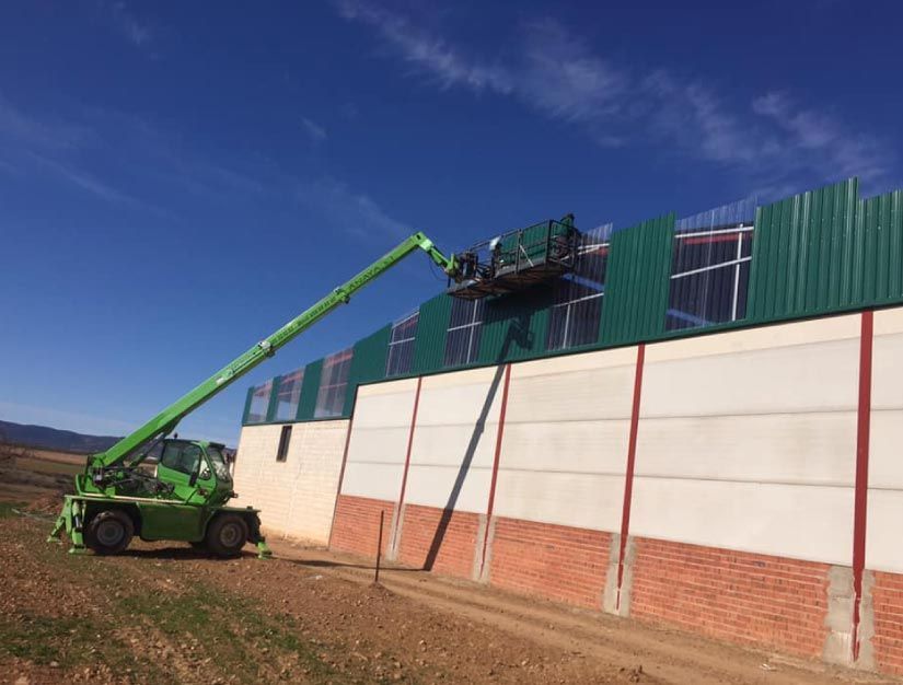Una grúa verde está trabajando en el costado de un edificio.
