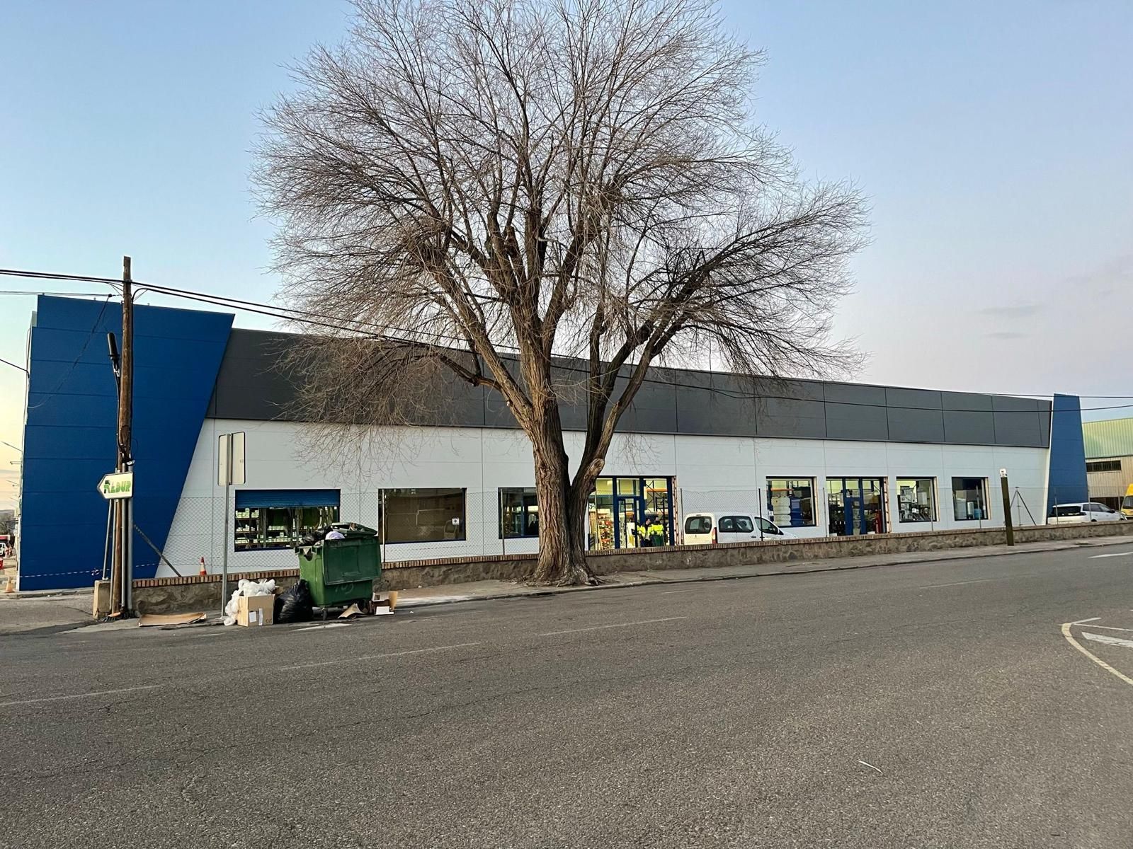 Un gran edificio con un árbol delante.