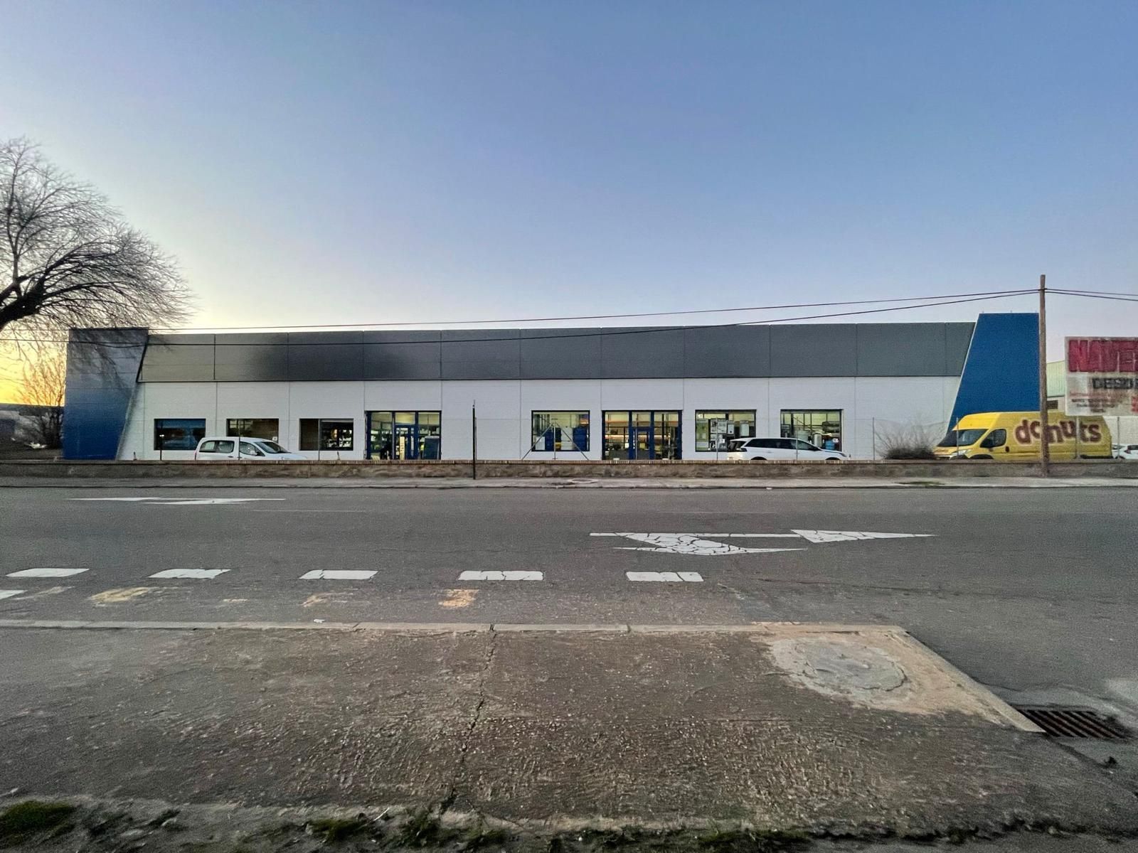 Un gran edificio está situado al costado de la carretera, al lado de una calle.
