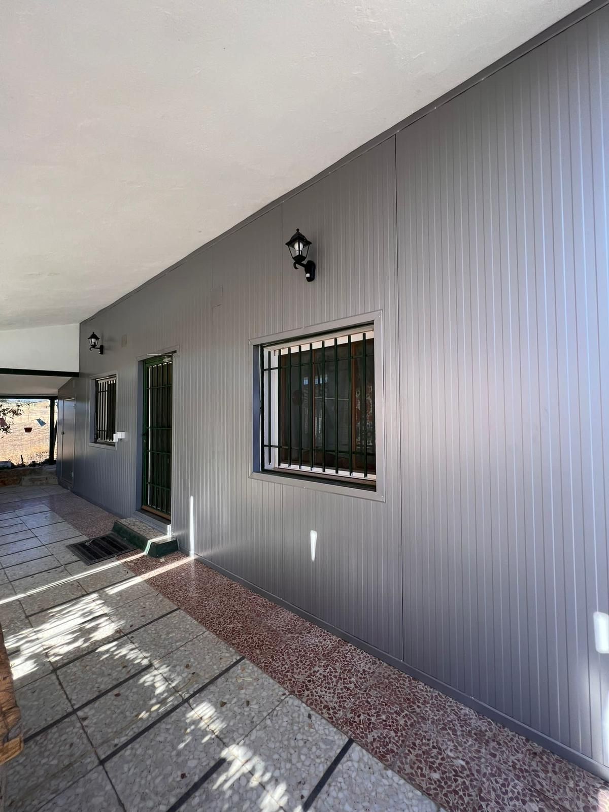 Una casa con una pared gris y una ventana al costado.