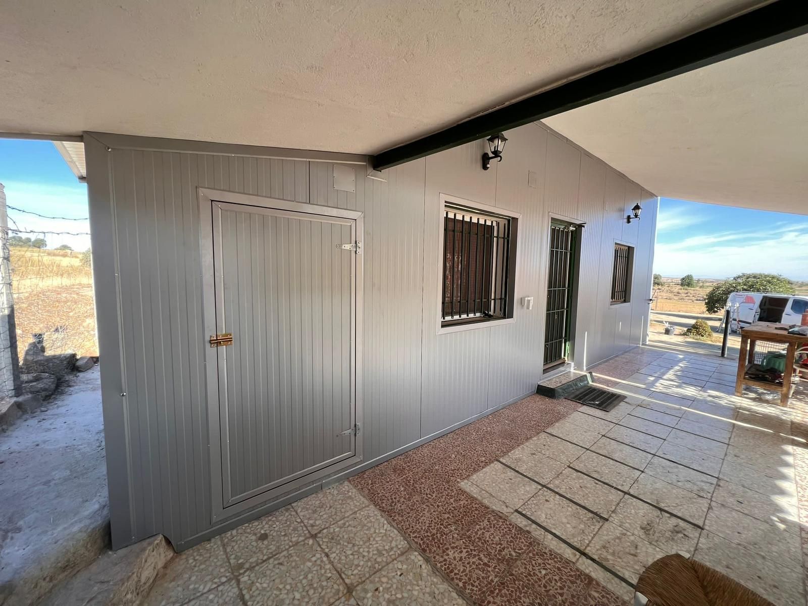 Un edificio gris con una puerta y una ventana al costado.