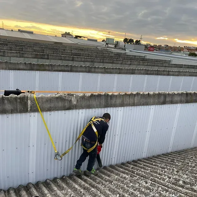 Un hombre que lleva un arnés de seguridad está de pie sobre un tejado.
