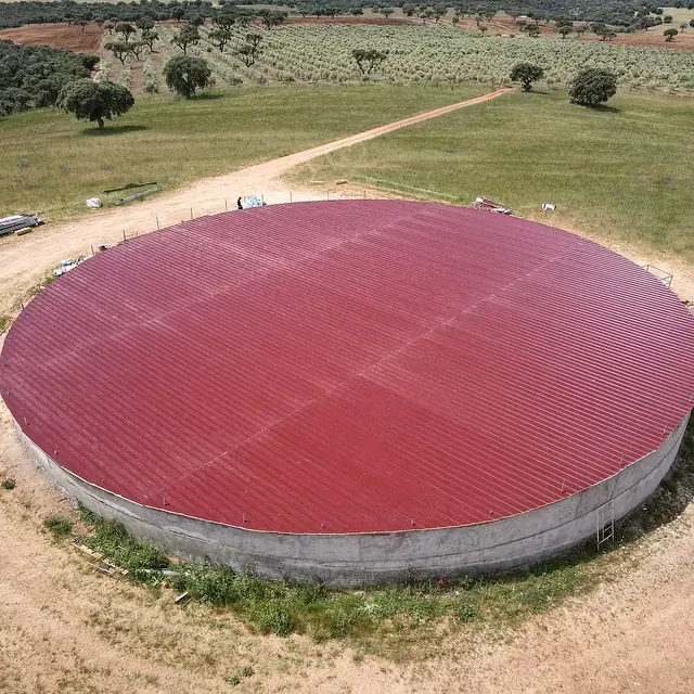 Un gran edificio redondo con techo rojo está en medio de un campo.