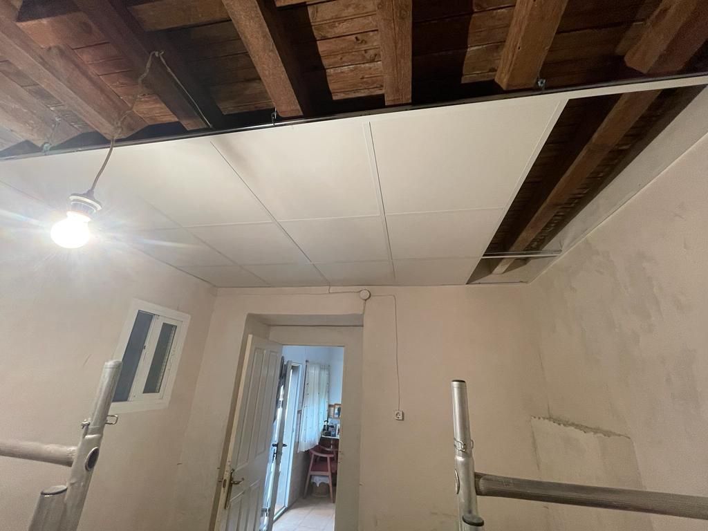 Una habitación con techo de madera y una lámpara colgando del techo.