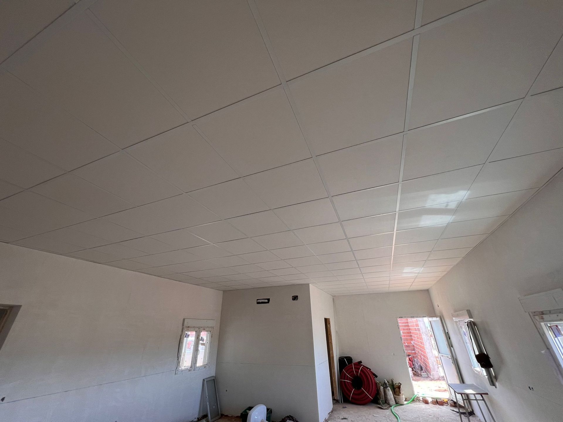 Una habitación con un techo blanco y una silla roja en ella.