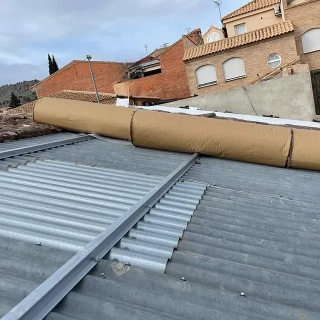 Un gran trozo de cartón está colocado encima de un techo de metal.