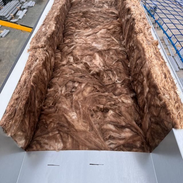 Una pila de lana marrón reposa sobre una superficie blanca.