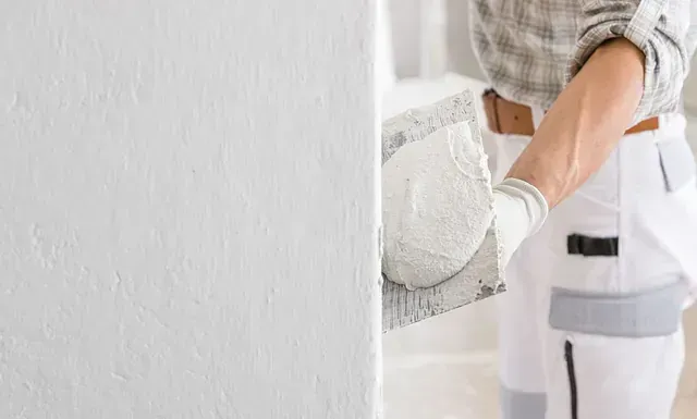 Una persona está enyesando una pared con una paleta.
