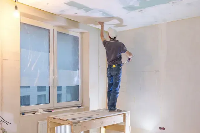 Un hombre está enyesando el techo de una habitación.