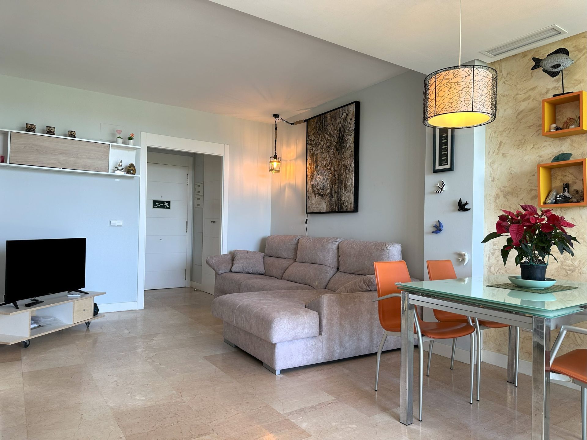 Una sala de estar con un sofá, una mesa, sillas y un televisor.