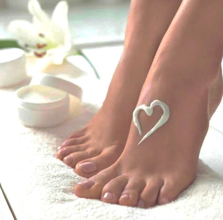 Fußpflegestudio, zwei Frauenfüße, am linken Fuß ein Herz aus Creme