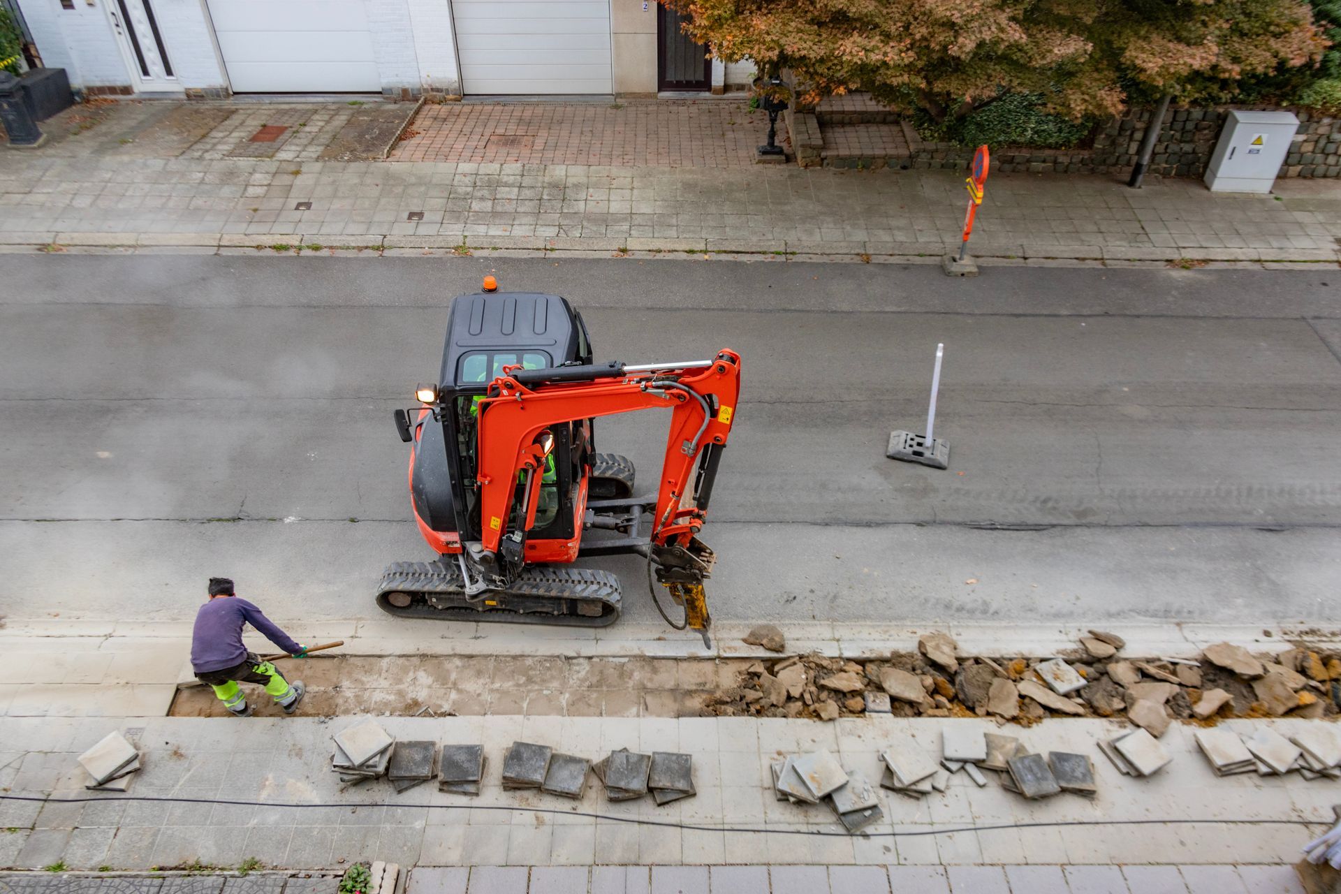 Une pelleteuse et un ouvrier enlèvent le revêtement d'une rue de la ville.