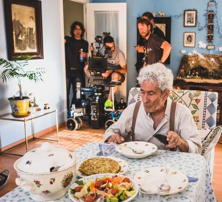 Un anciano está sentado en una mesa con platos de comida.