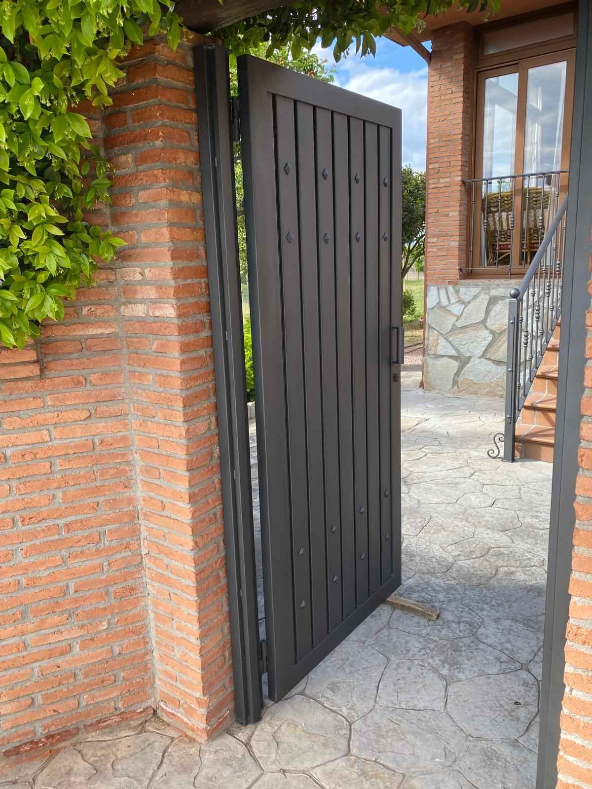 Una puerta negra está abierta hacia una pared de ladrillos.