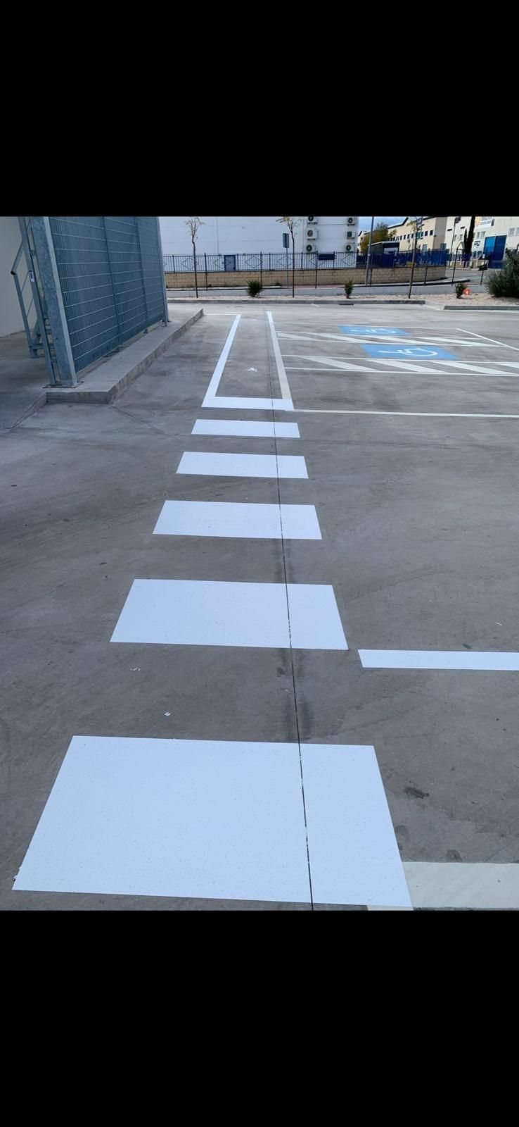 Un paso de peatones blanco está pintado al costado de un estacionamiento.