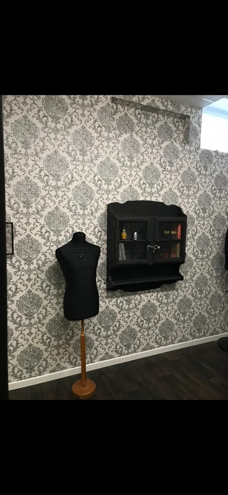 Una habitación con un maniquí y un estante en la pared.