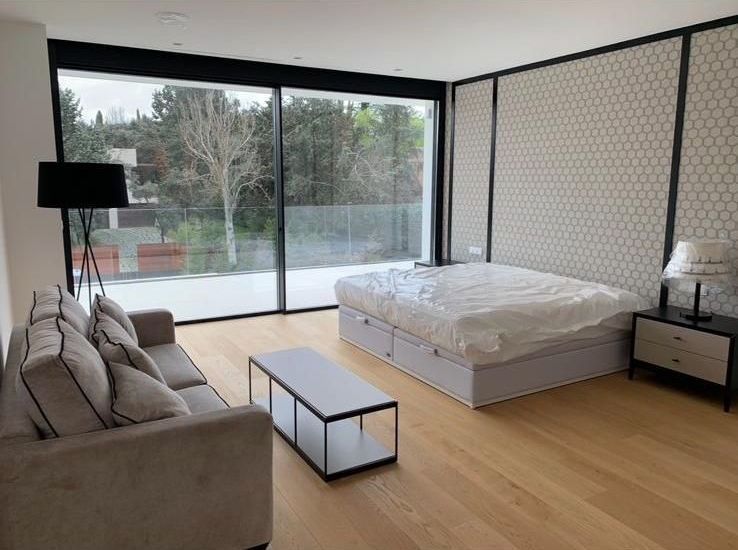 Un dormitorio con cama, sofá, mesa de café y puertas corredizas de vidrio.