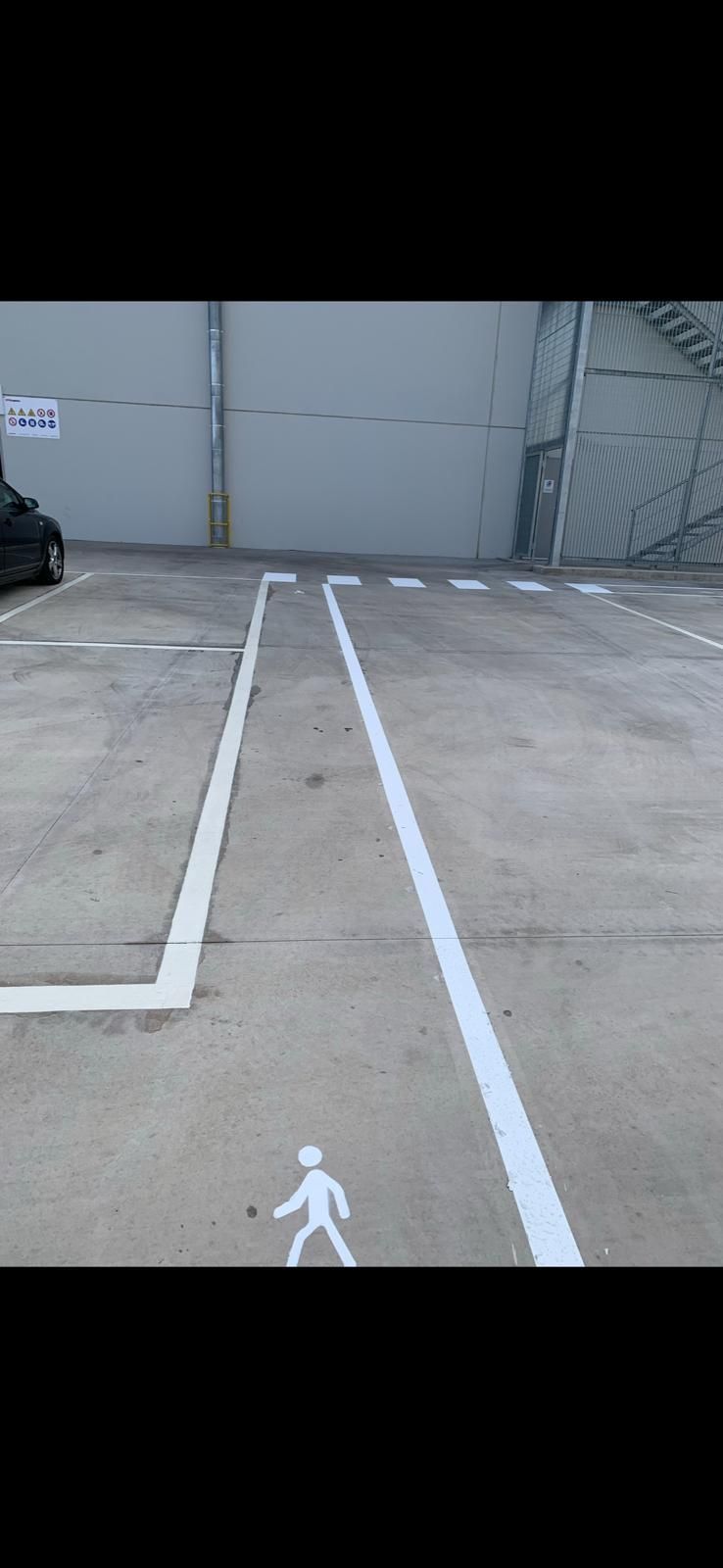 Un estacionamiento con una línea blanca y un dibujo de una persona en el suelo.
