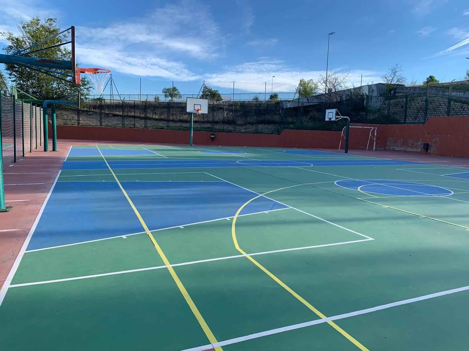 Una cancha de baloncesto con una valla y un aro de baloncesto