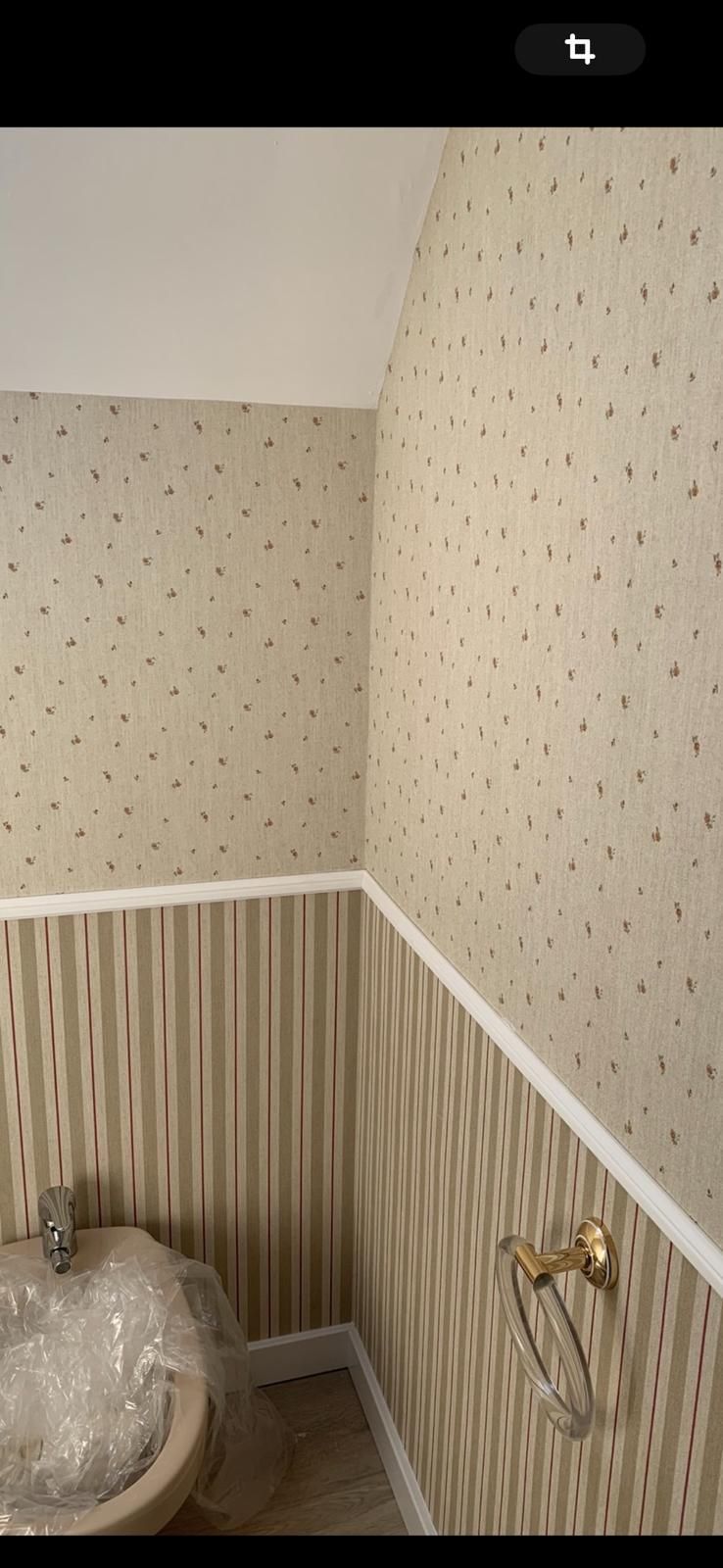 Un baño con papel pintado a rayas y un inodoro.