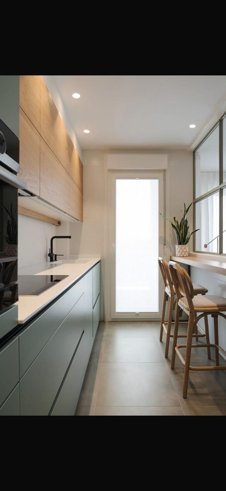 Una cocina con fregadero, estufa, sillas y una gran ventana.