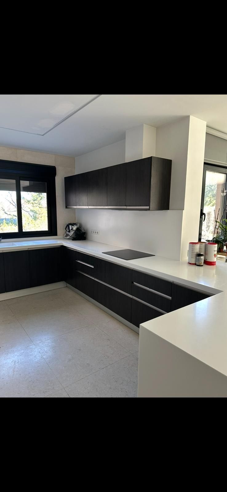 Una cocina con gabinetes negros y encimeras blancas.