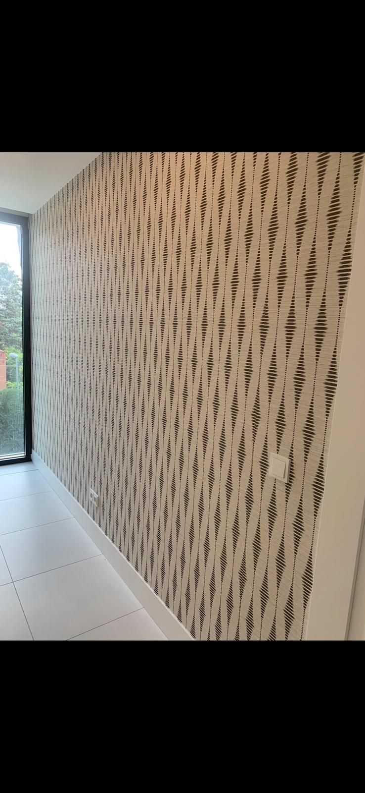 Un pasillo con una gran ventana y una pared con un patrón.