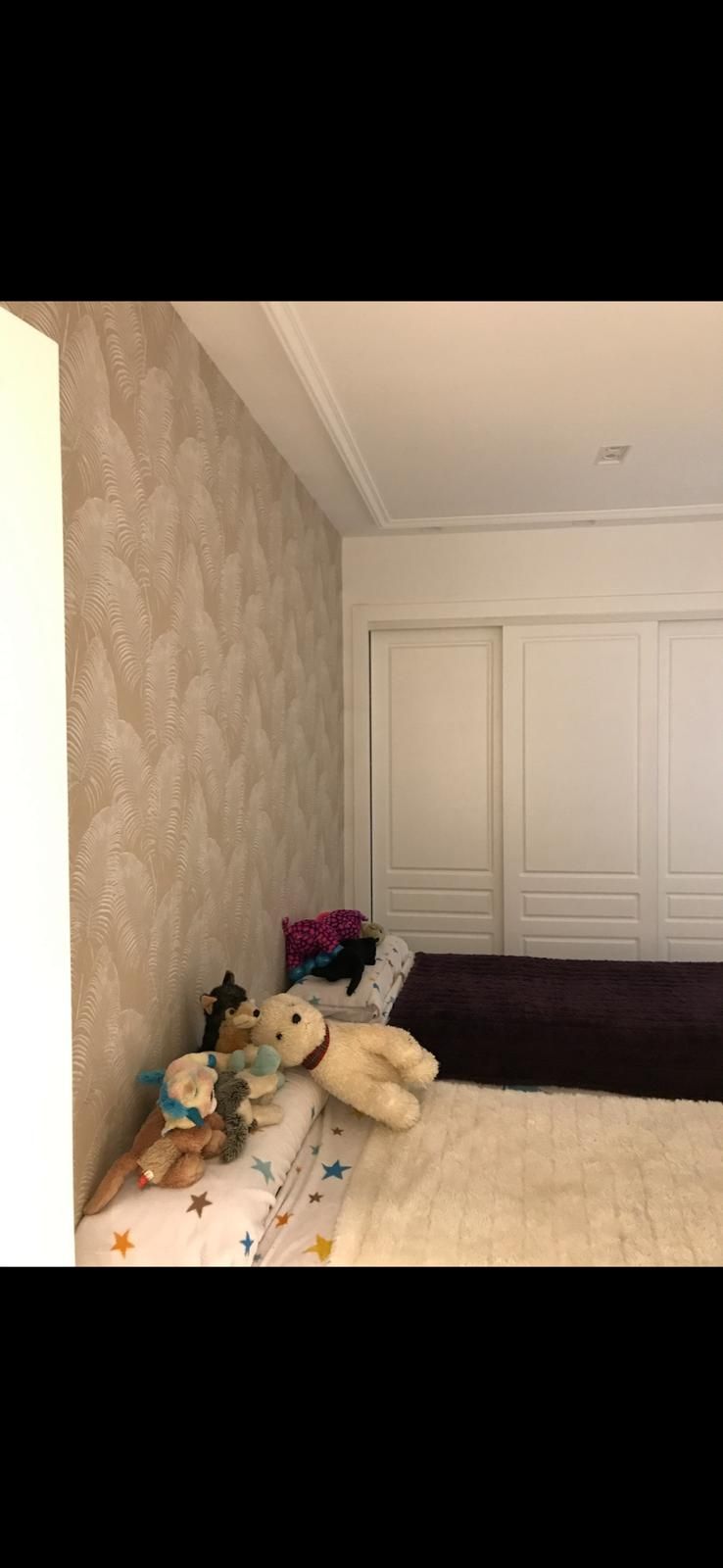 Un dormitorio con una cama, un armario y animales de peluche en la cama.