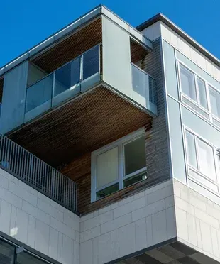 Un edificio con un balcón y un cielo azul al fondo.