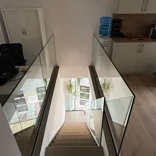 Una escalera con barandilla de vidrio que conduce al segundo piso de una casa.