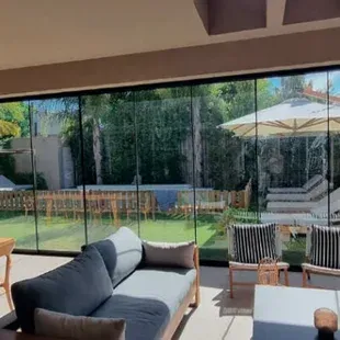 Una sala de estar con un sofá, sillas, sombrillas y una gran ventana.