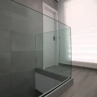 Una escalera con barandilla de cristal y una ventana.