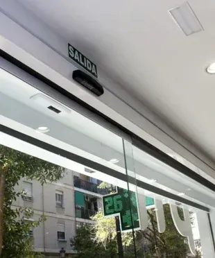 Una puerta corrediza de vidrio con un cartel de salida encima.