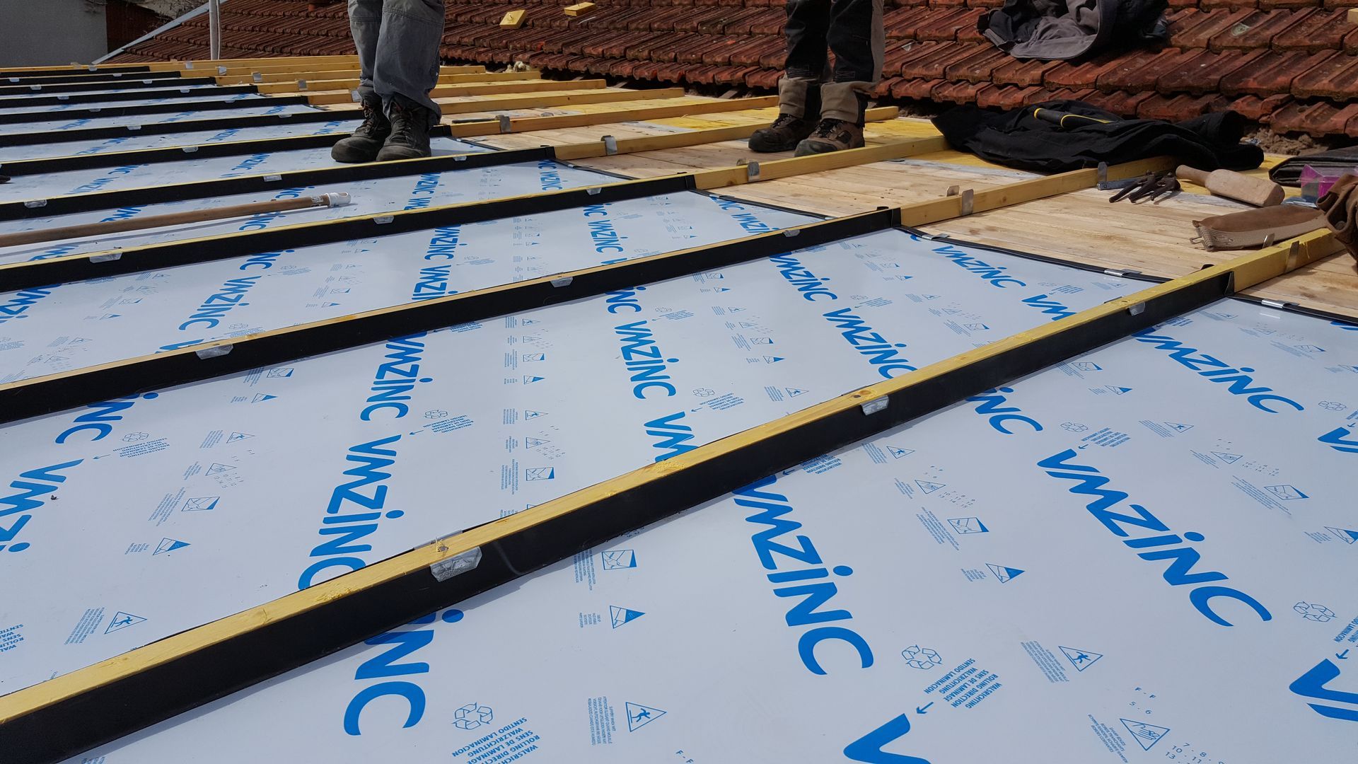 Couvreurs debout sur un toit sans tuile d'une extension de maison