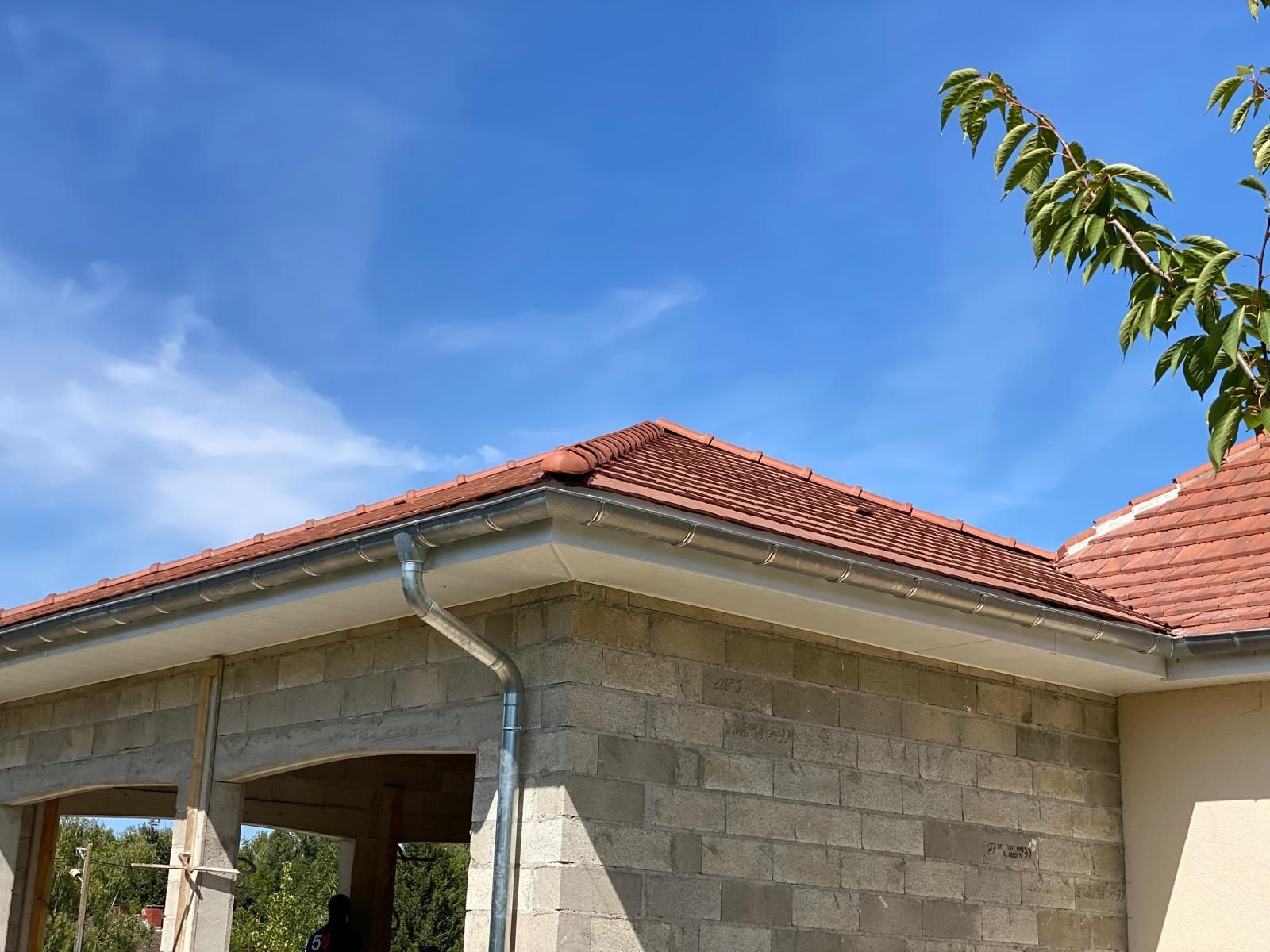 Couverture en tuile d'une maison aux murs en parpaing apparent