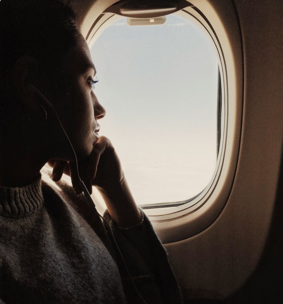 Una persona que viste una blusa blanca y un chaleco color canela sostiene un pequeño globo terráqueo de colores entre ambas manos.