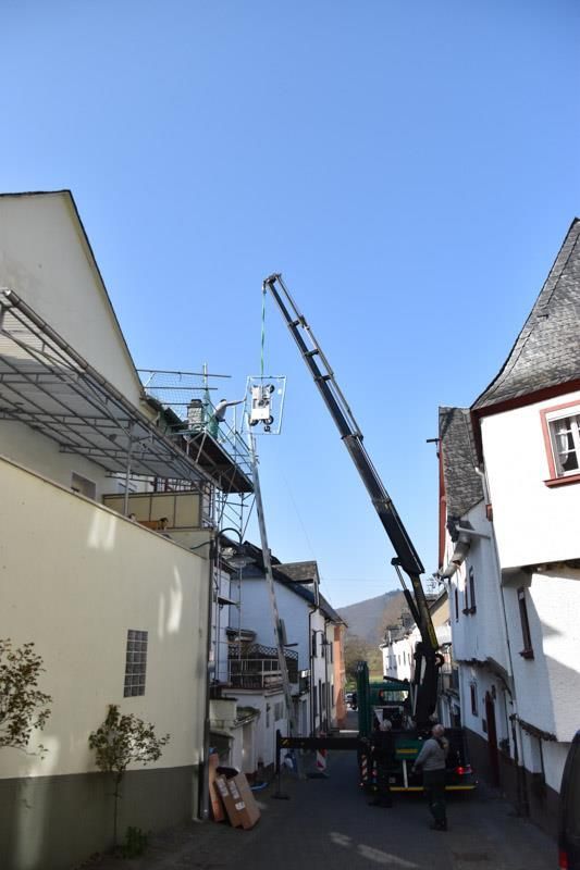 Ein Kran hebt eine Leiter in ein Gebäude