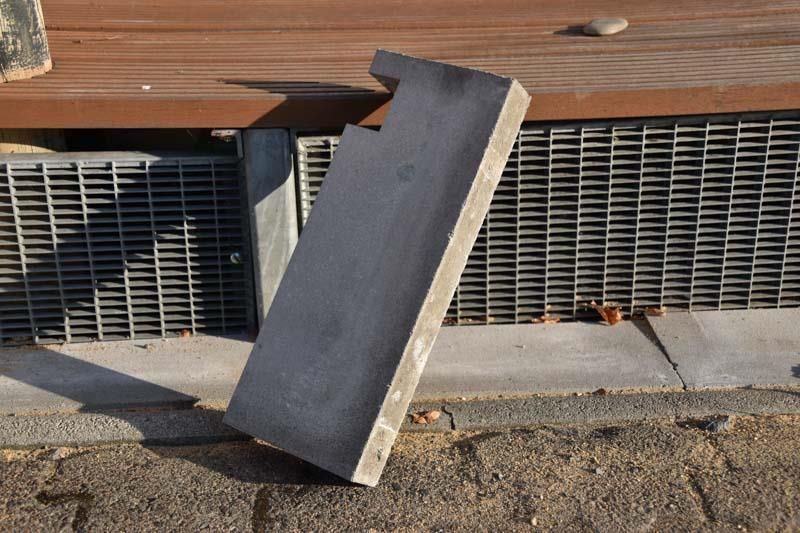 Ein Stück Beton liegt auf dem Boden neben einem Metallgitter