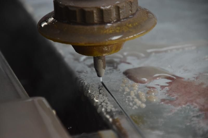 Eine Maschine schneidet ein Stück Metall mit Wasser