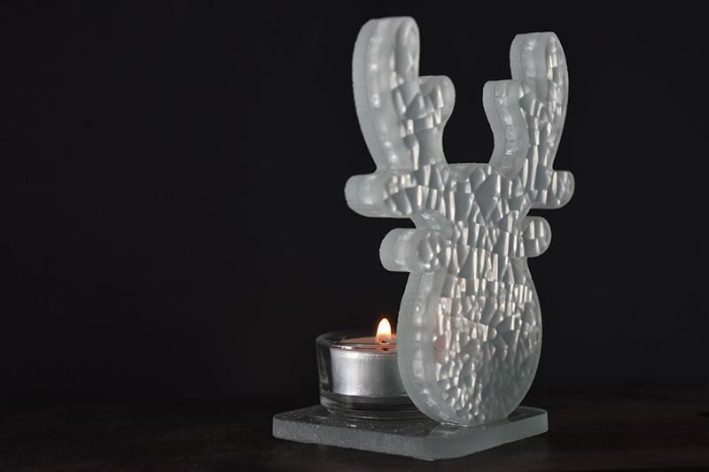 Ein Kerzenständer aus Glas mit Rentiermotiv und einer brennenden Kerze darin