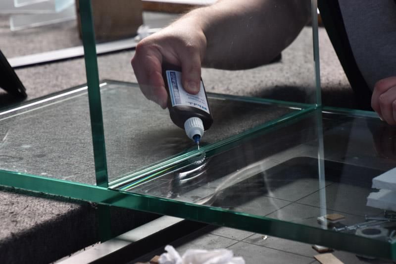 Eine Person trägt Klebstoff auf ein Stück Glas auf