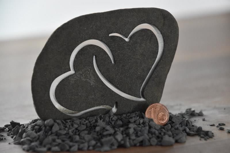 Zwei Herzen sind in einen Felsen neben einem Penny geschnitzt