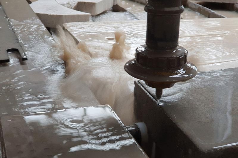 Eine Maschine schneidet ein Stück Metall, aus dem Wasser austritt.