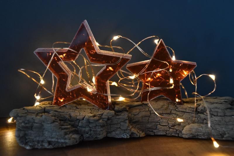 Drei Sterne leuchten auf einem Stück Holz