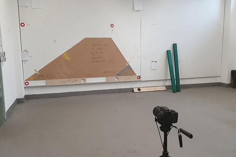 Ein leerer Raum mit einem Dreieck an der Wand und einer Kamera auf einem Stativ